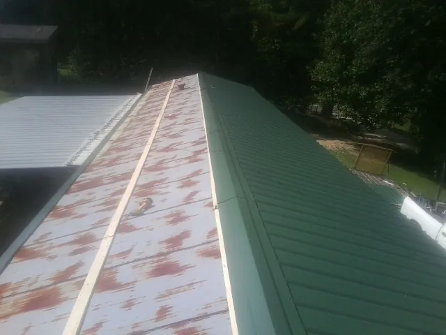 Old rusted panels beside newly installed green metal roofing — Wind Damage Roof Repair by Roofing Brothers in Hoffman