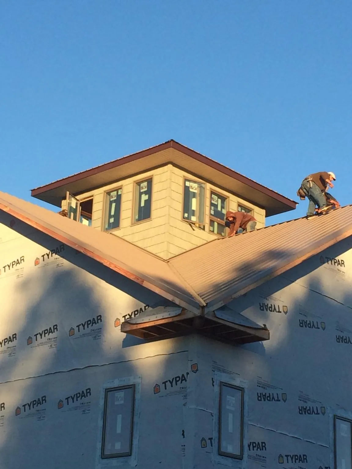 Roofers working around a rooftop cupola on a new metal roof at sunset — Roof Waterproofing in Hoffman by Roofing Brothers
